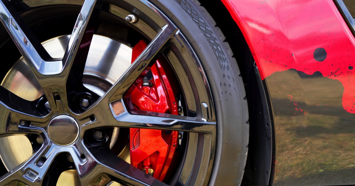 A close-up of the wheels and tires of a red sports car with alloy wheel rim, low-profile tires, and red brake caliper.