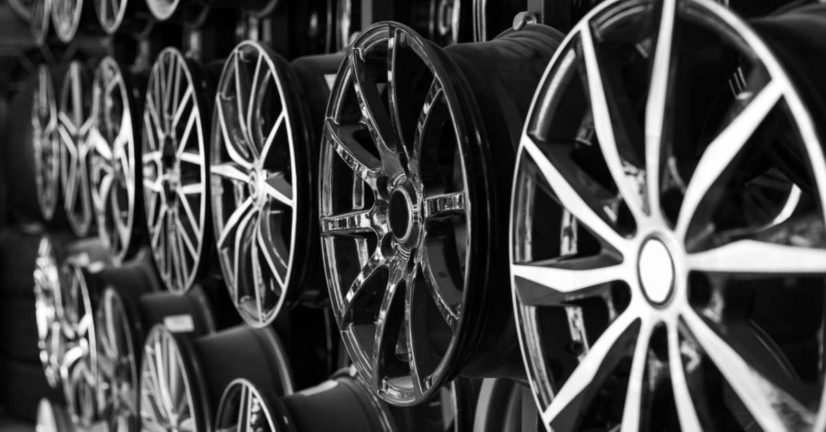 A wall of hung alloy wheels for vehicles. Each wheel is shiny with differing styles and patterns.