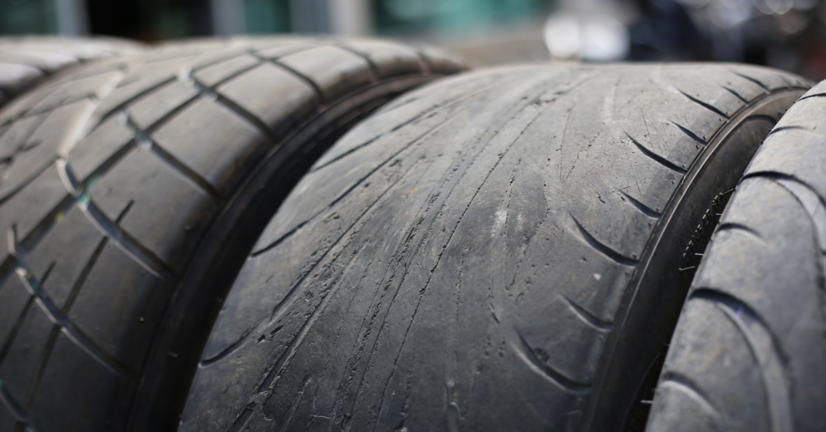 A close-up of several tires stacked next to each other. The middle tire is very worn, with its center completely worn down.