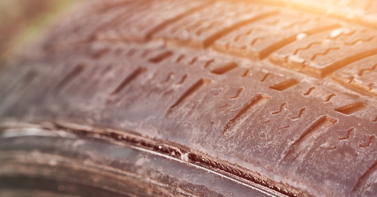 A close-up of an older tire's outer edge. The sidewall has a deep crack along the seam of the edge.