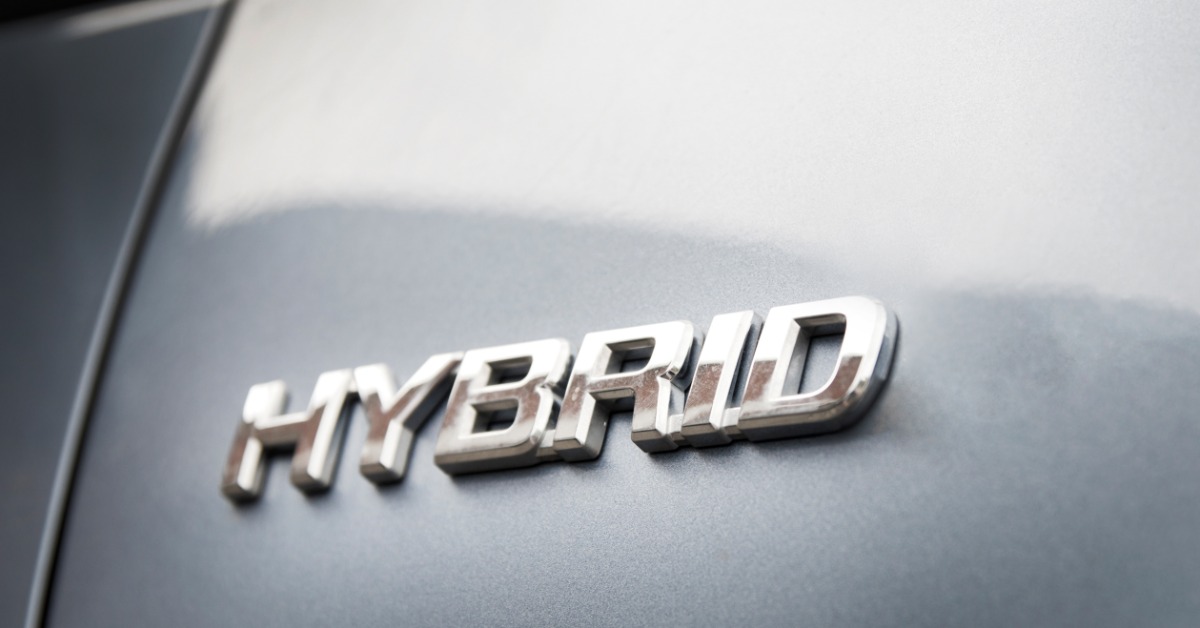 A close-up of the exterior of a modern vehicle with a chrome badge that reads "HYBRID" near the trunk door.