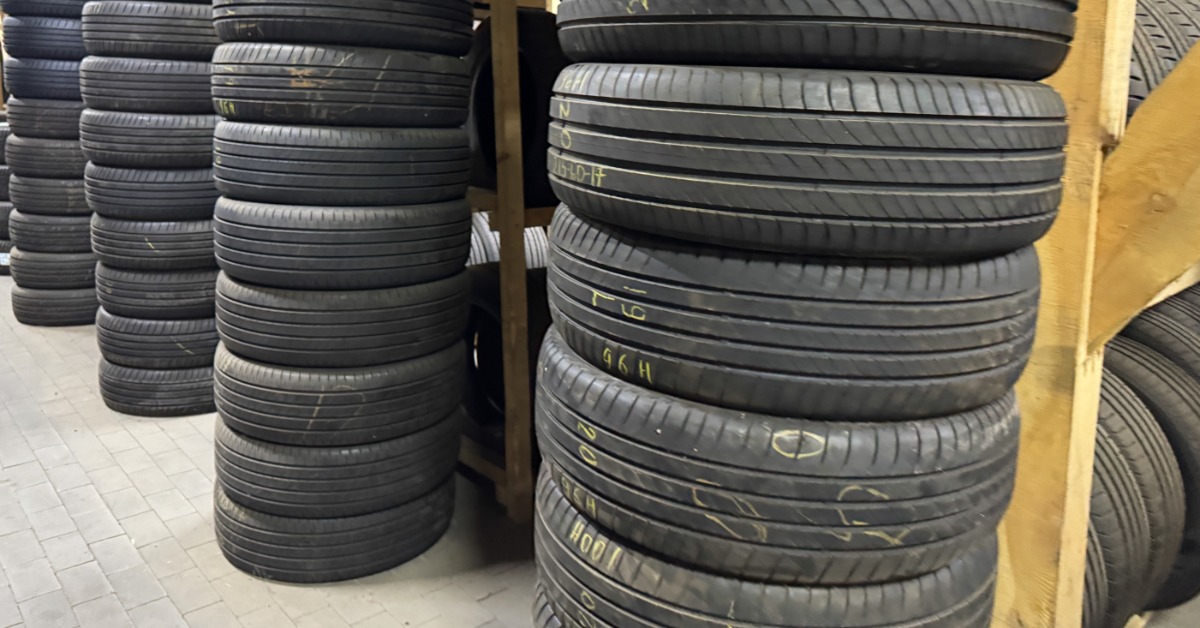 A shop or warehouse floor with stacks of tires next to shelves of tires. Some of the tires have yellow markings.