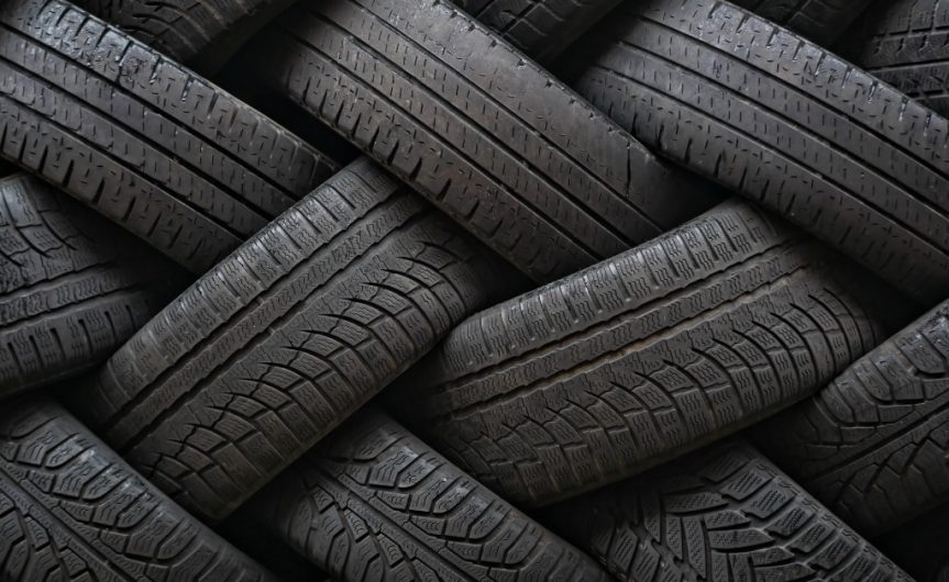 Several different types of tires with various forms of wear lie in opposite directions of each other to create a weave pattern.