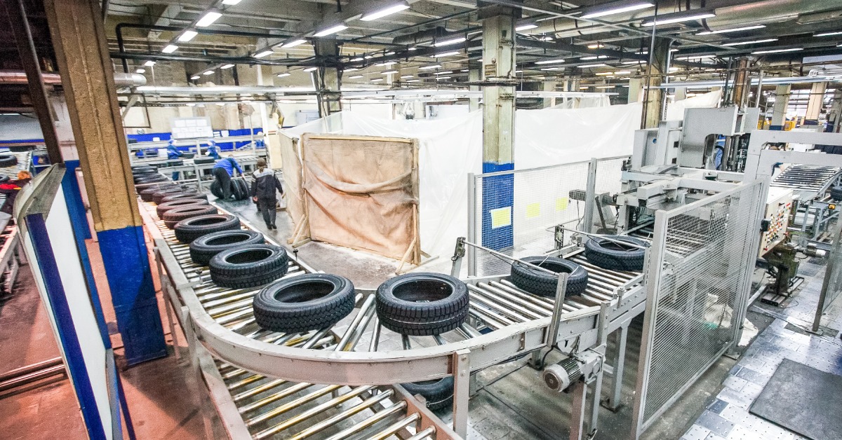 A wide view of an automotive tire production facility, with numerous tires moving on a roller conveyor line.