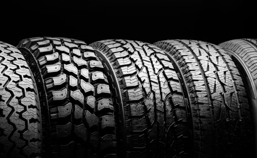 A lineup of five different off-road tires, each featuring distinct tread patterns and depth, against a black background.