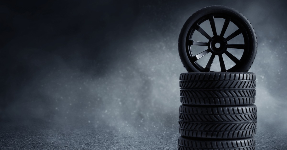 A black tire standing upright on a stack of three more black tires. White fog fills the area behind the stack.