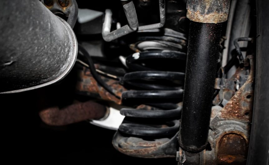 A close-up of a vehicle's rear suspension system with a focus on the shock absorber and coil spring.