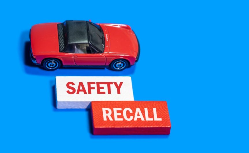 A close-up of a miniature red car model next to two red-and-white blocks that say 