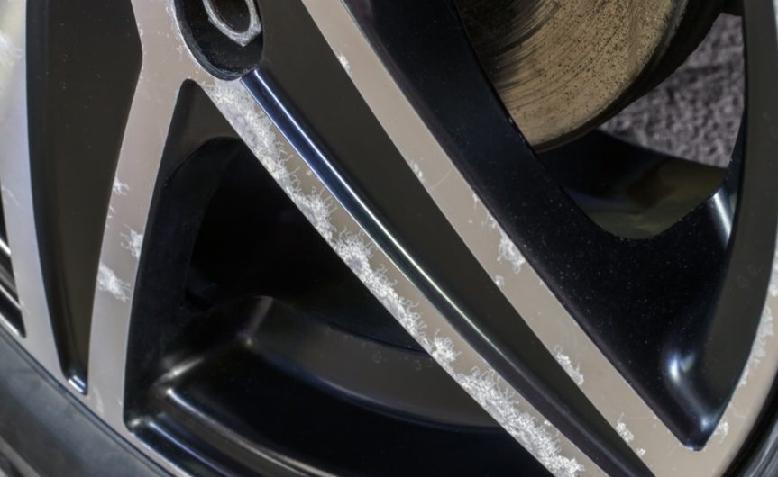 A close-up of an automotive wheel and tire showing corrosion and damage on the wheel hub and brake caliper.