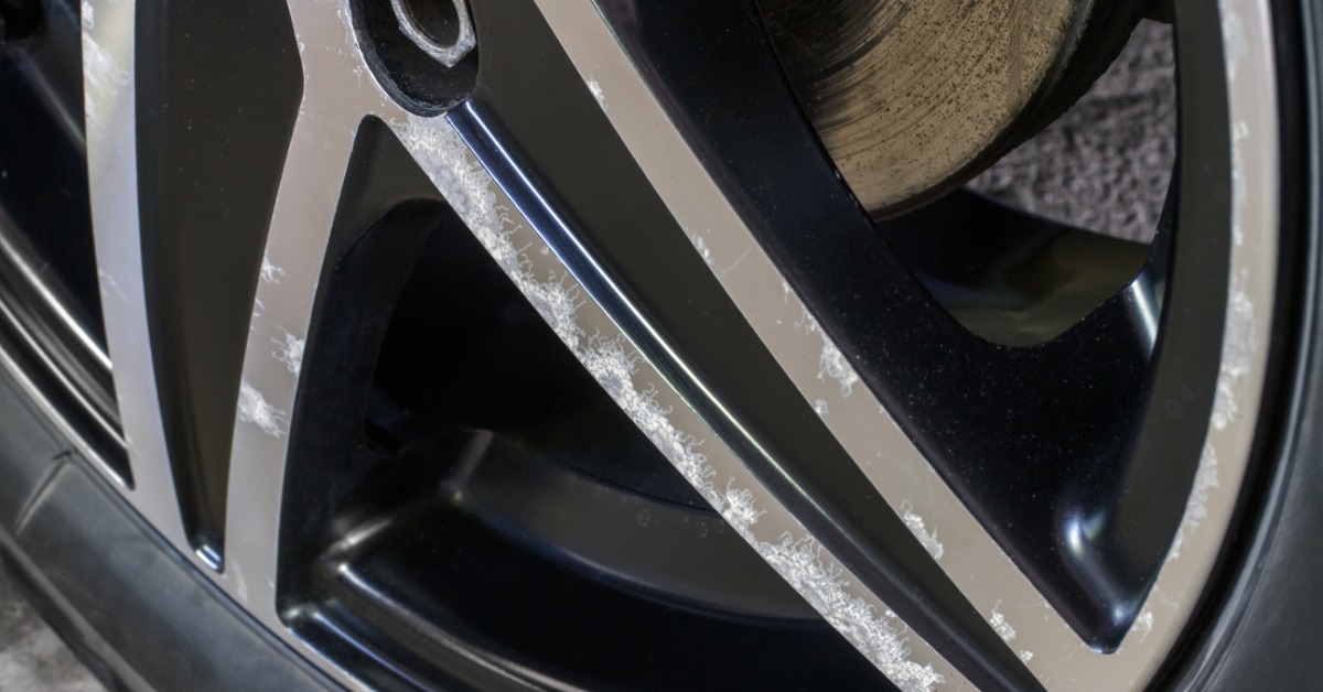 A close-up of an automotive wheel and tire showing corrosion and damage on the wheel hub and brake caliper.