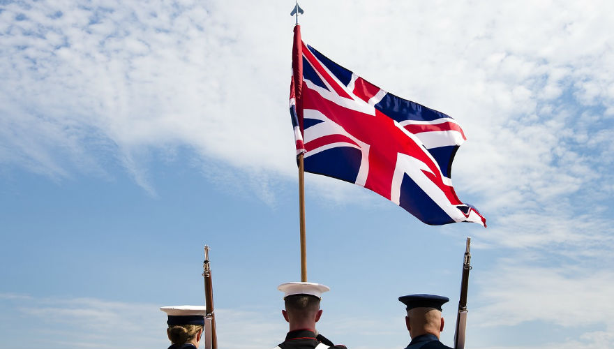 Imagen de una mujer y dos hombres izando la bandera de Inglaterra