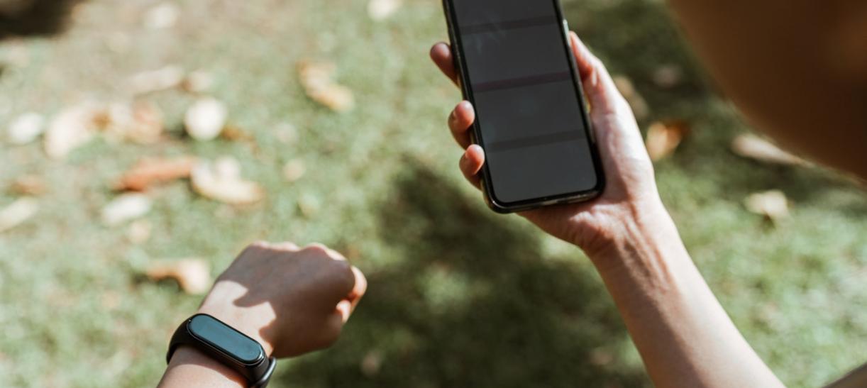 Persona viendo la pantalla de su celular y reloj inteligente para conocer el estado de su salud