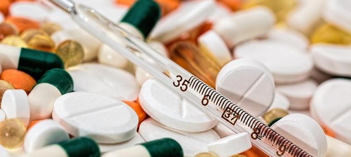 Imagen de termómetro, tabletas cápsulas y otros medicamentos.