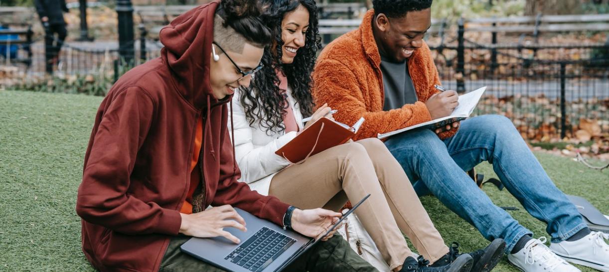Foto de tres jóvenes estudiantes en un campus universitario.