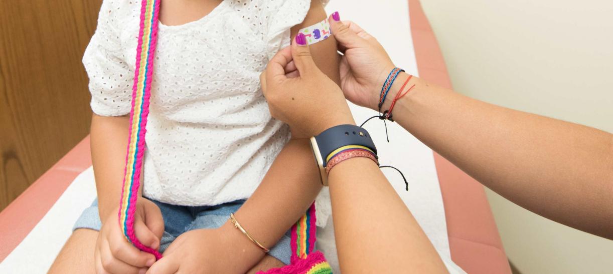 Foto de niña a quien le ponen una cura en el brazo luego de ser vacunada.