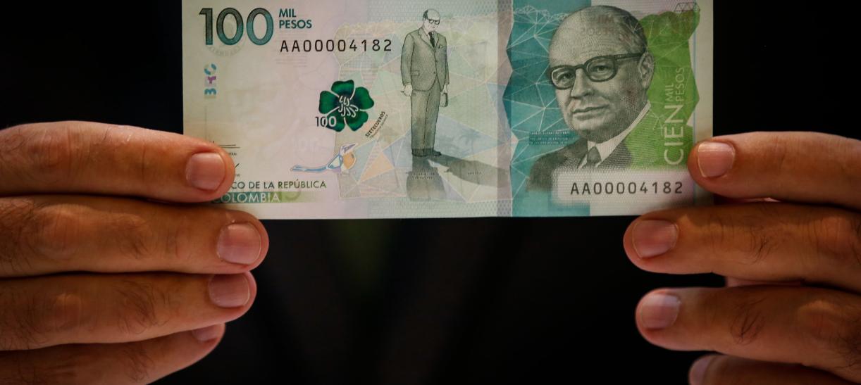 Billete de $100.000 sostenido por par de manos. Ilustra nota sobre billetes falsos.