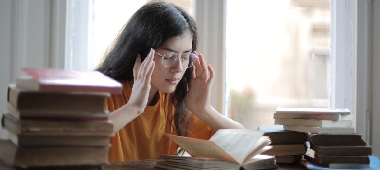 Mujer joven rodeada de libros. Ilustra nota sobre Jornada de Soluciones ICETEX.