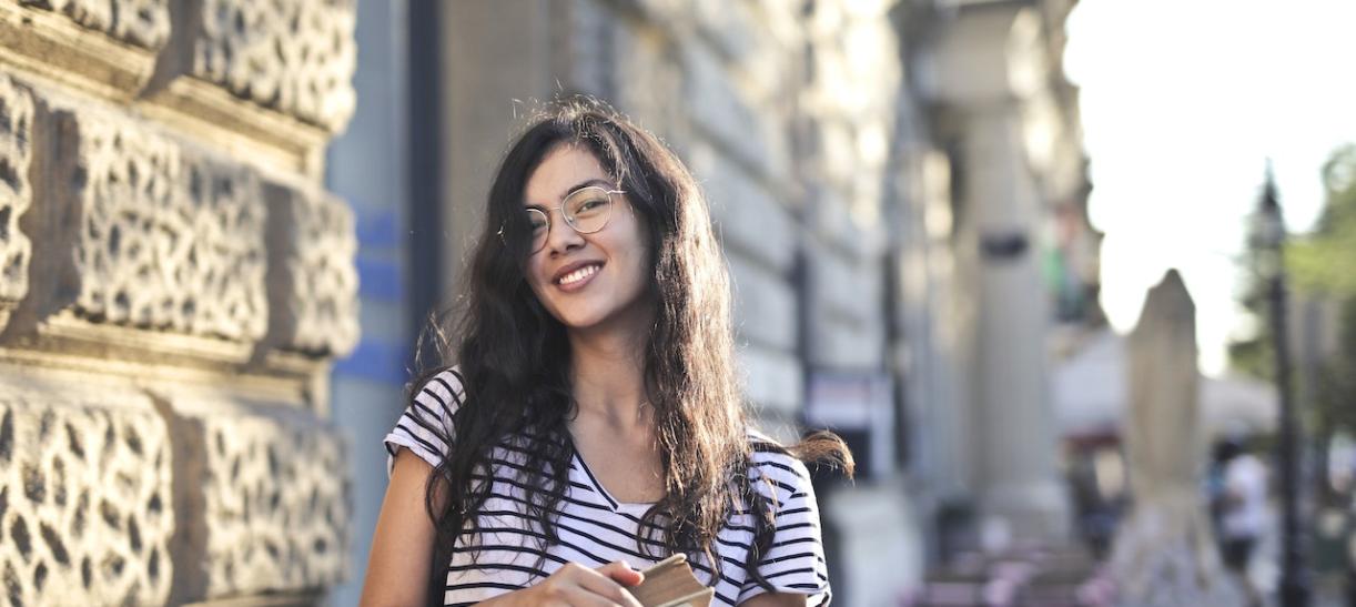 Foto de mujer sonriendo mientras sostiene unos libros. Ilustra nota de becas en Chile.