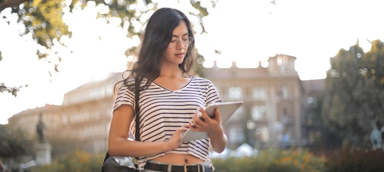 Mujer joven con ipad en la mano. Ilustra nota sobre becas OEA 2023.