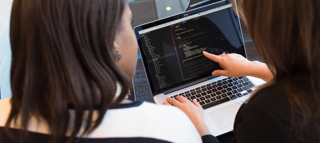 Dos mujeres frente a la pantalla de un computador portatil o laptop.