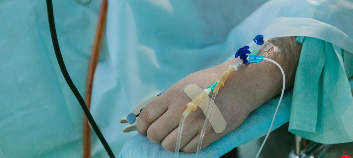 Mano de una persona recibiendo suero en una camilla de hospital.