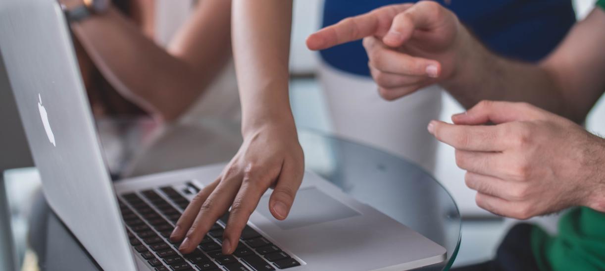 Manos de personas apuntando a la pantalla de un computador. Ilustra nota de becas Google 2023.