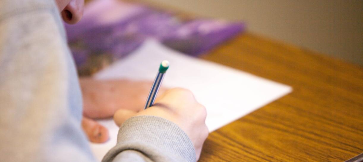 Joven con una hoja y un lápiz. Ilustra nota sobre Pruebas Saber Pro y Saber TyT.