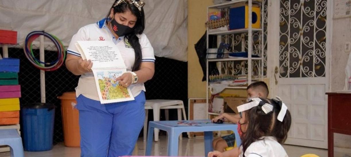 Madre comunitaria enseña a una niña en un hogar del ICBF.