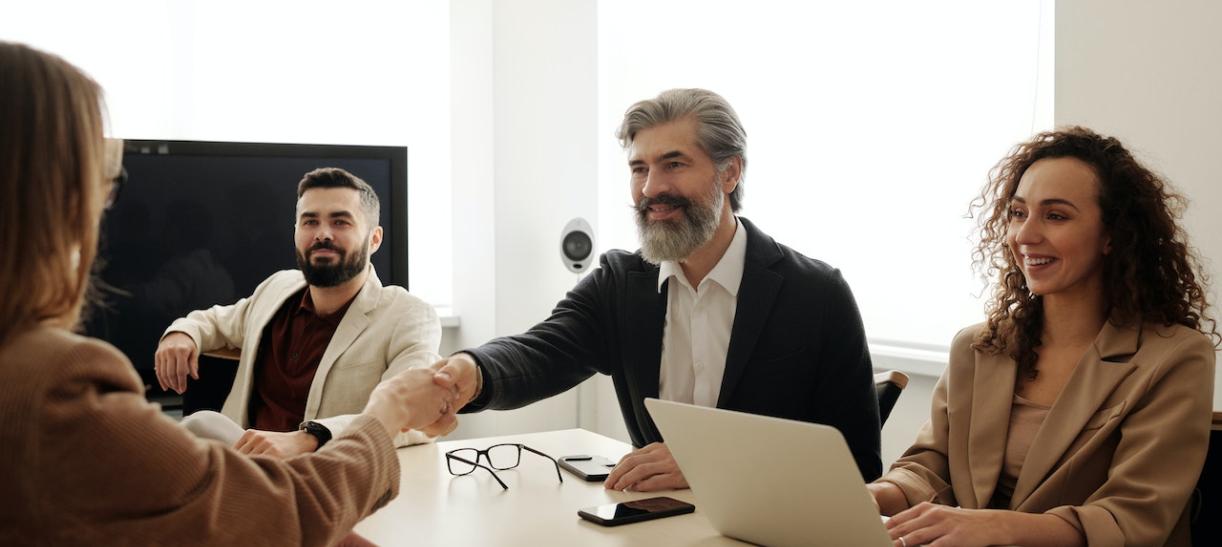 Hombre estrecha la mano de una mujer en una oficina. Ilustra nota sobre empleo en superintendencias.