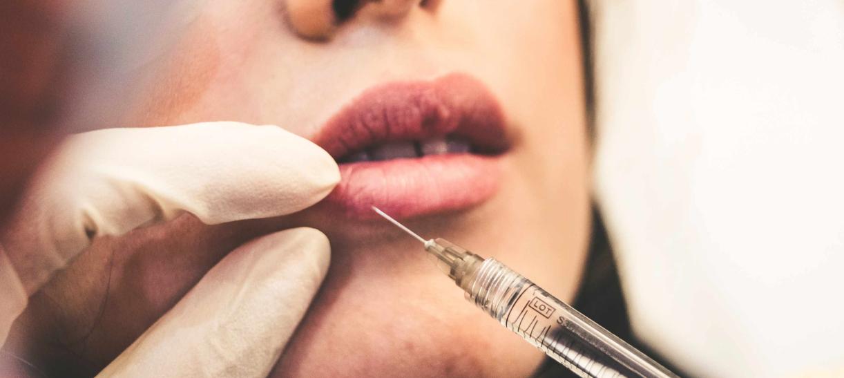 Persona aplicando en una paciente una sustancia para aumentar sus labios - Ley sobre el uso de biopolímeros