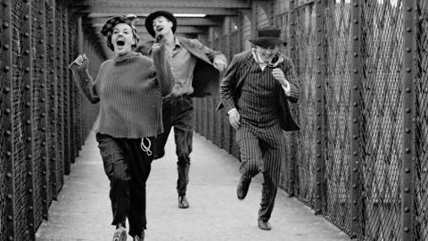 Tres personas corren por un puente peatonal en la película "Jules y Jim" de Truffaut