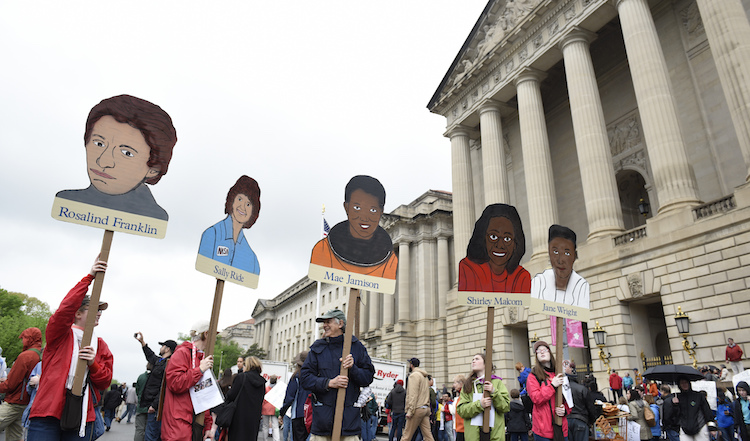People hold signs of poineering women in science at the D.C. March for Science