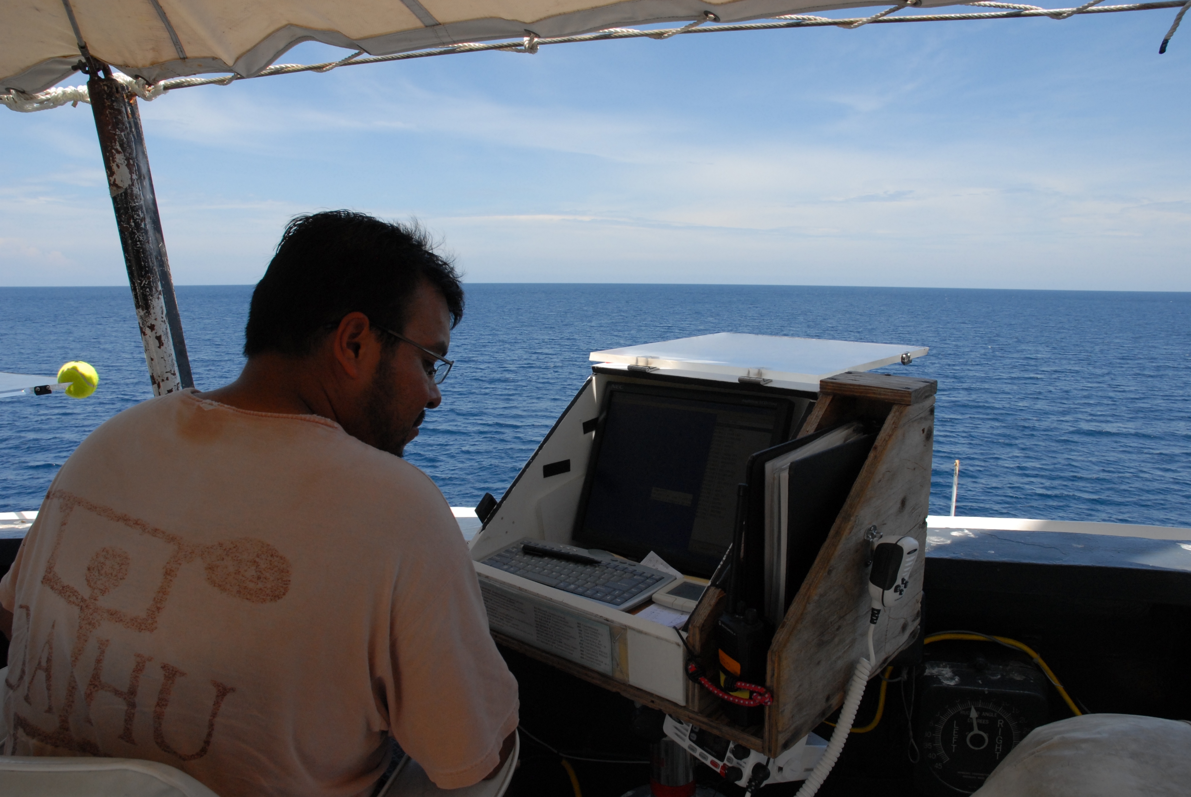 A member of the scientific party enterin marine mammal sighting data into adatabase while observing from the bridge wing of the NOAA ShipDAVID STARR JORDAN