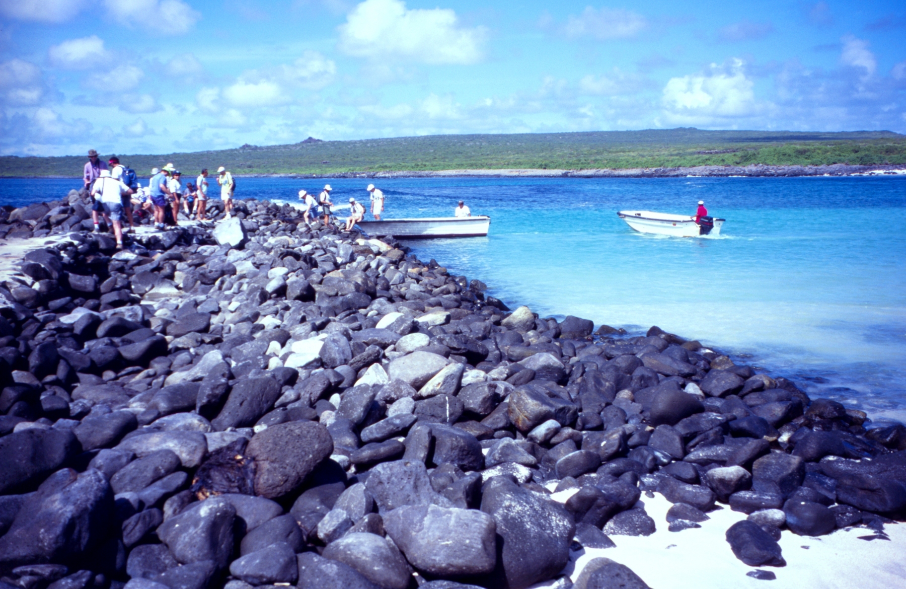 Eco-tourists with carmera s and packs debarking from skiff from cruise ship onboulder breakwater