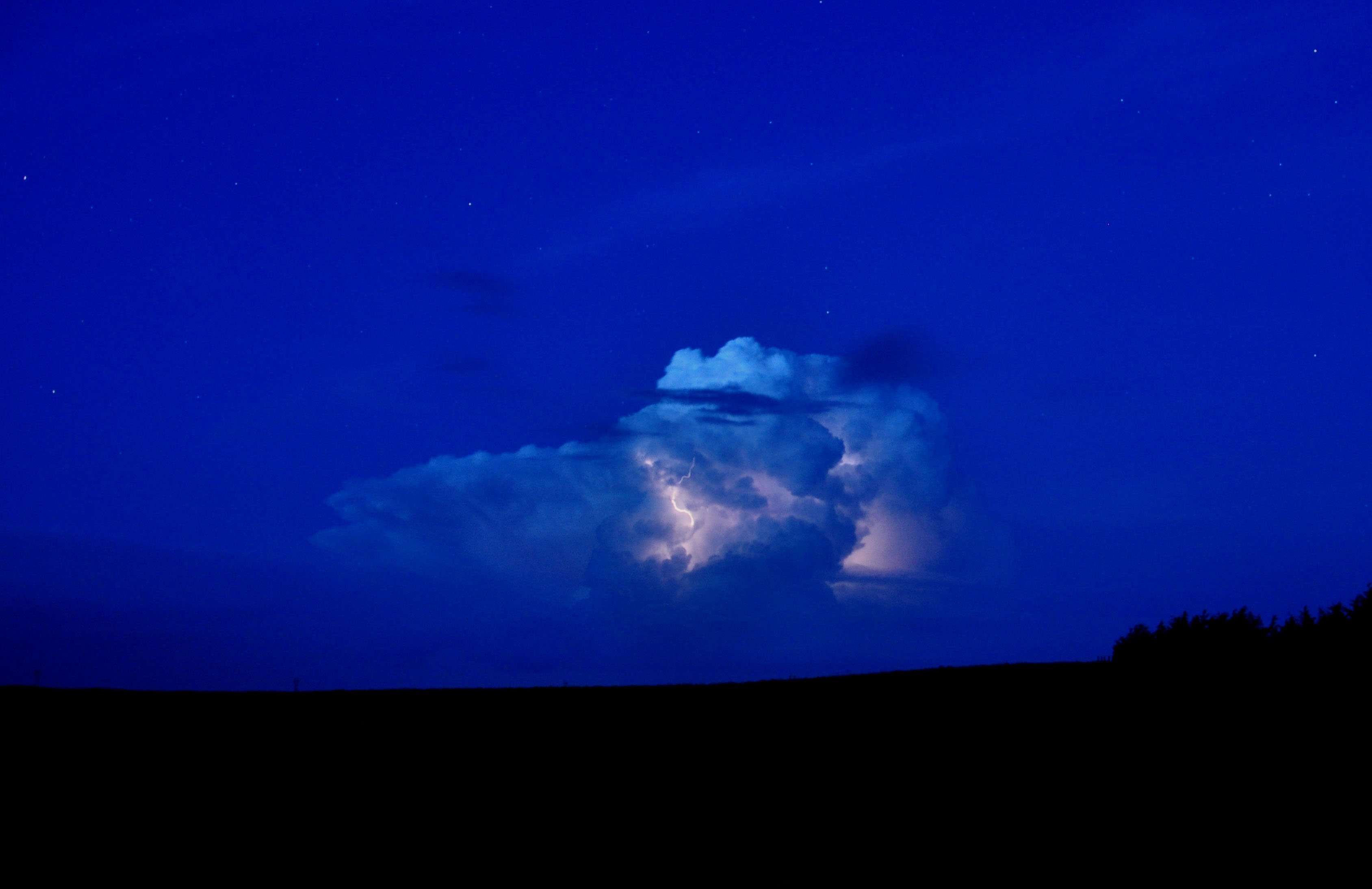 Supercell thunderstorm illuminated by lightning at night