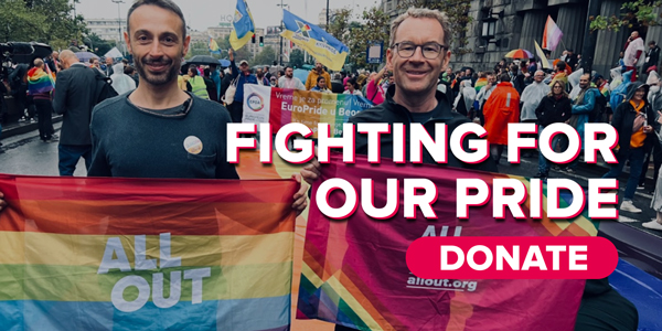 Matt and Yuri from All Out stand in the streets of Belgrade proudly holding flags while participating in Europride.
