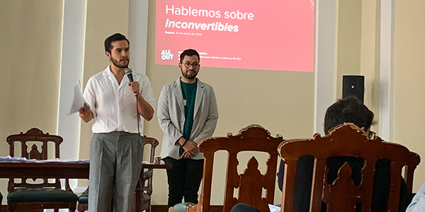 Andrés from All Out presents information in front of a screen projection that says Let's Talk about Inconvertibles in Spanish.