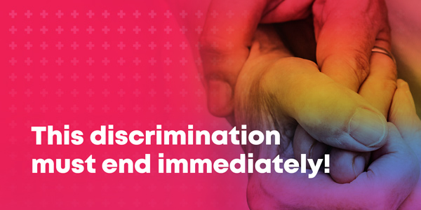 The picture shows two hands holding each other with a rainbow coloring. The text reads: This discrimination must end immediately!