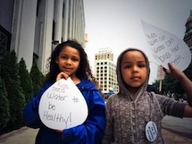 Detroit children holding signs demanding access to water for brushing teeth