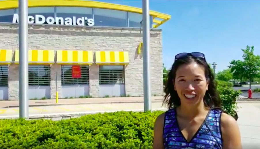 Dr Elaine Leung standing in front of a McDonalds restaurant smiling with a blue sky