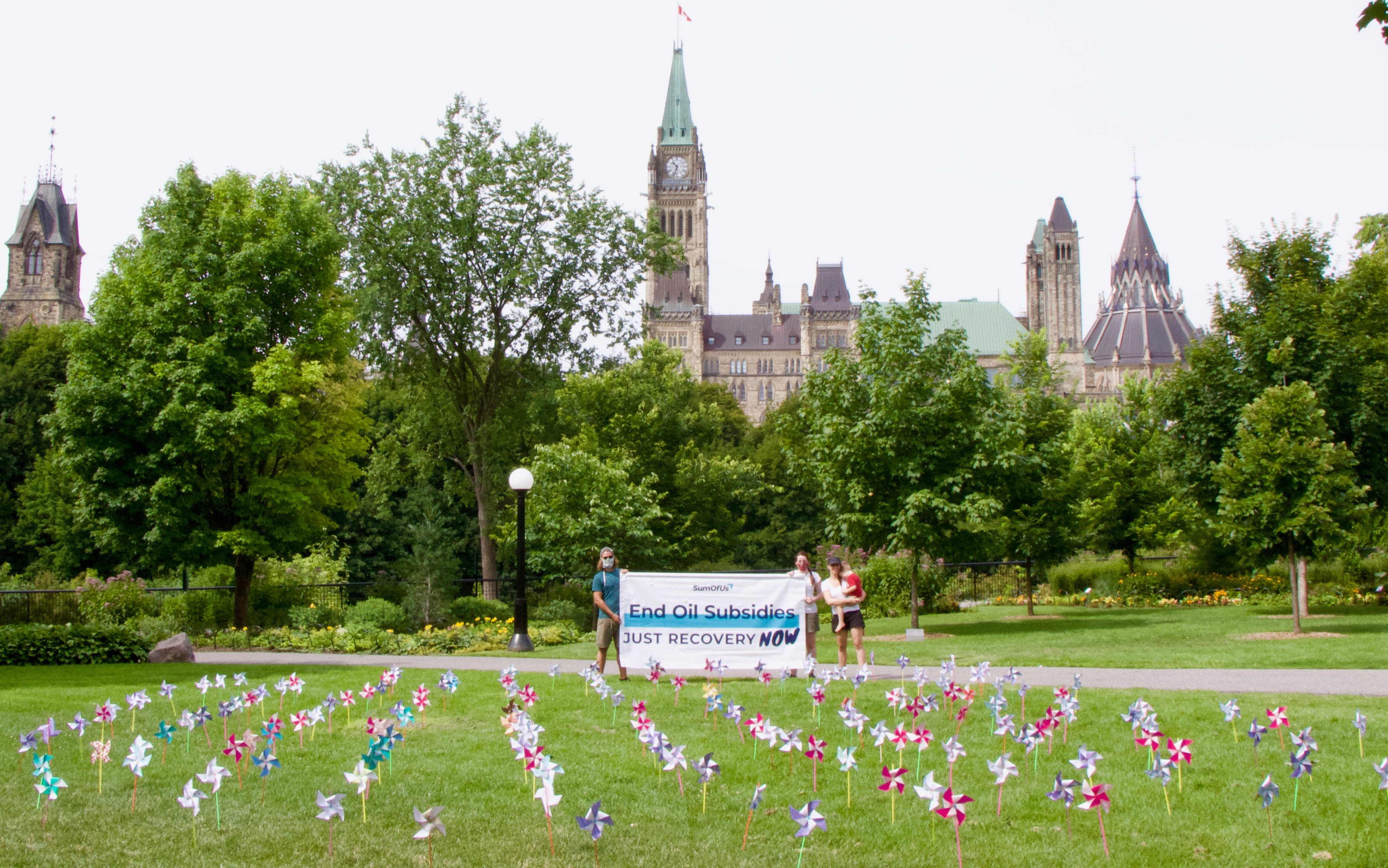 Windmills on the lawn with banner outside Parliament Hill