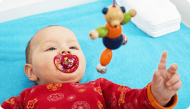 Reaches for toy with one hand