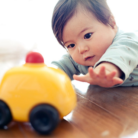 Baby can reach for toy with one hand