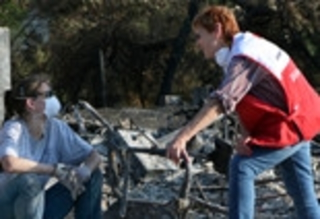 A Red Cross worker comforts a resident whose home was destroyed by Western Wildfires