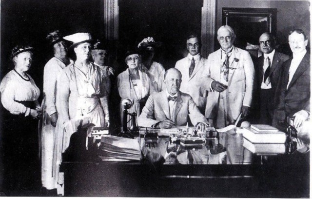 The Nineteenth Amendment (Speaker of the House Frederick H. Gillett signing the suffrage resolution, surrounded by members of the National American Woman Suffrage Association and leading pro-suffrage members of the House).