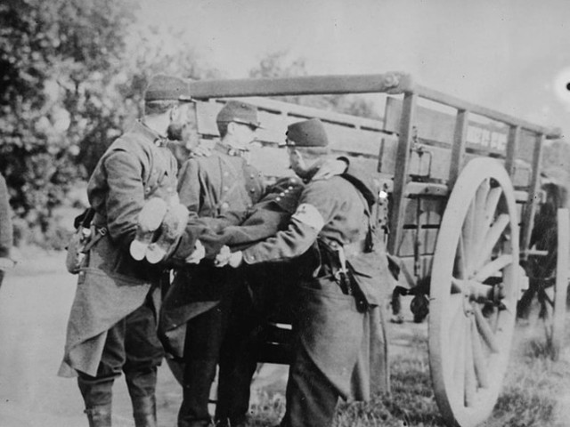 Soldados franceses recolhem ferido em cidade da Bélgica, em 1914