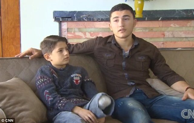 Syrian man carries his injured brother to Turkey