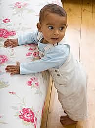 Pulls self up while bracing selves on furniture