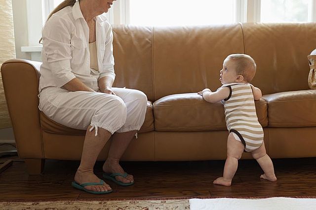 Baby is walking while holding onto furniture