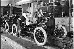 Henry Ford builds cars on assembly line